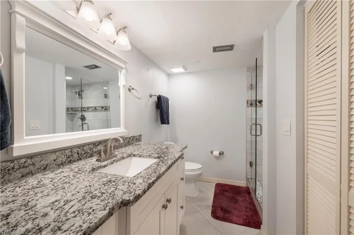 Bathroom featuring toilet, an enclosed shower, tile patterned floors, and vanity