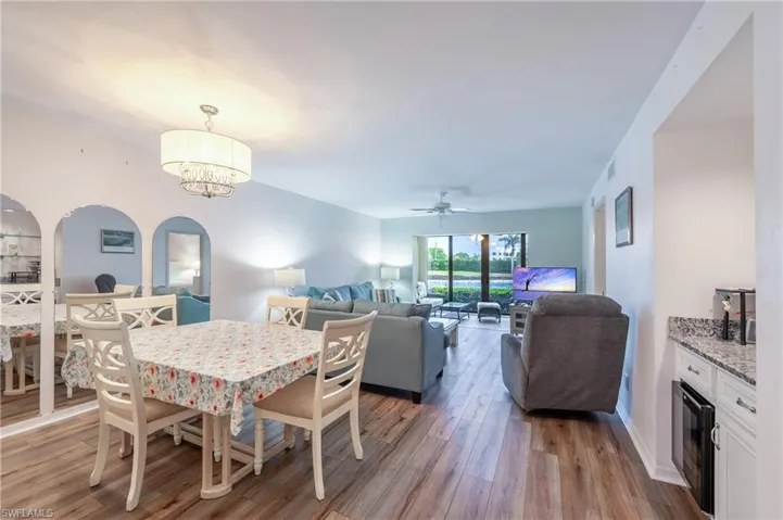 Dining space featuring light wood-type flooring, ceiling fan with notable chandelier, and wine cooler
