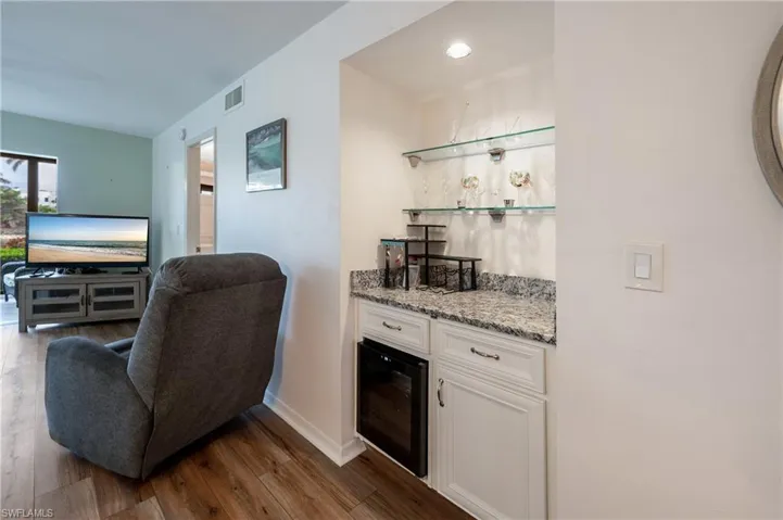 Bar featuring white cabinets, light stone countertops, and wood-type flooring