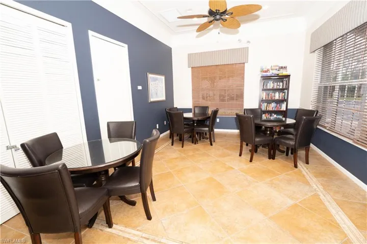 Dining space with light tile patterned flooring, a raised ceiling, ornamental molding, and ceiling fan
