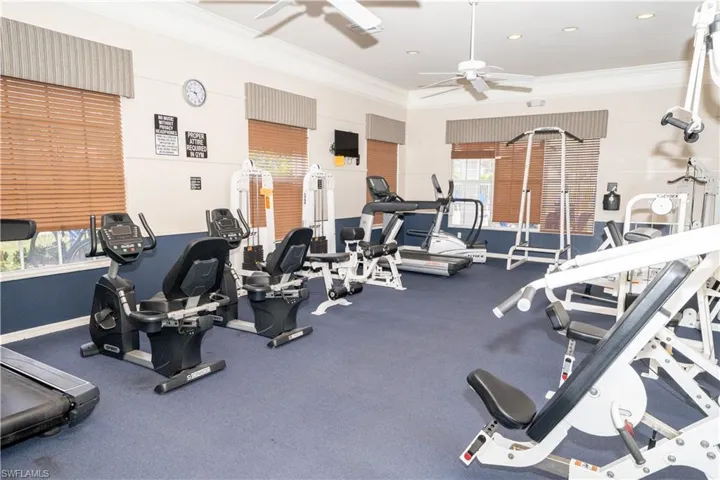 Gym with ornamental molding and a ceiling fan