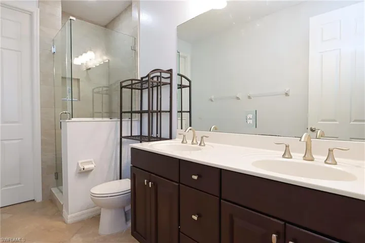 Bathroom with tile patterned flooring, toilet, a shower with door, and vanity