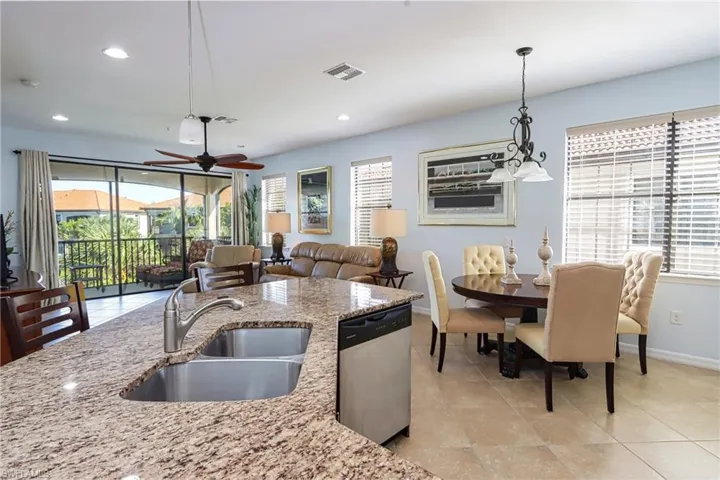 Kitchen with light stone countertops, sink, ceiling fan, pendant lighting, and stainless steel dishwasher