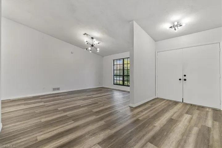 Foyer featuring wood-type flooring, lofted ceiling, and an inviting chandelier