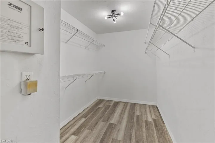 Walk in closet with hardwood / wood-style flooring