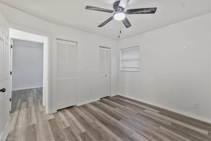 Unfurnished bedroom featuring ceiling fan, light hardwood / wood-style flooring, and two closets