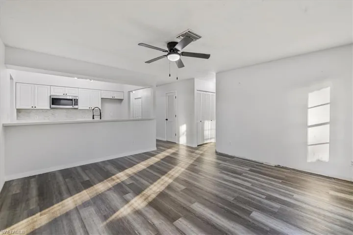 Unfurnished living room with ceiling fan, sink, and dark hardwood / wood-style floors
