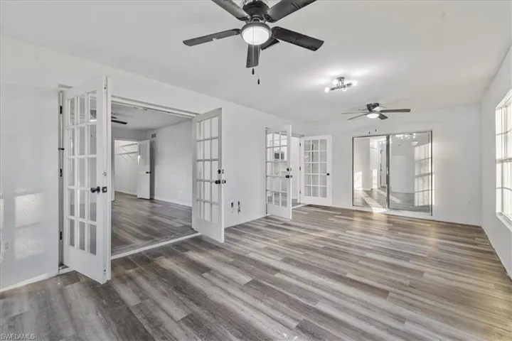 Empty room featuring french doors, ceiling fan, and wood-type flooring