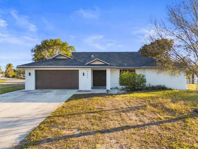 Single story home with a garage and a front lawn