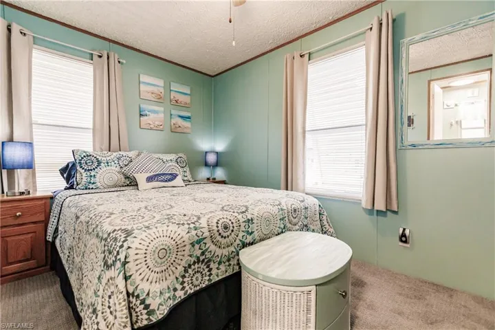 Bedroom featuring carpet flooring, multiple windows, and a textured ceiling