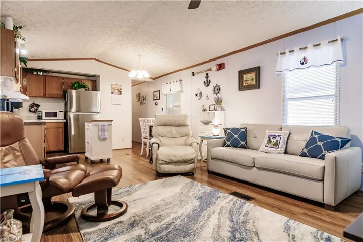 Living room with light laminate/ wood-style floors, crown molding, and lofted ceiling