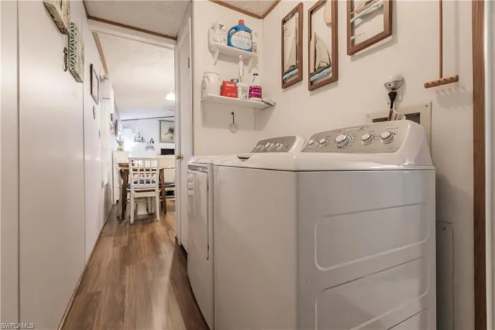 Laundry room conveniently located between primary bedroom and kitchen 2023 washing machine and dryer, and laminate / wood-style flooring