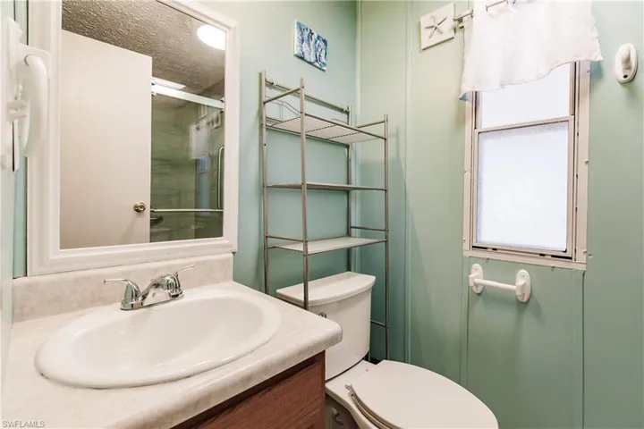 Bathroom featuring an enclosed shower, vanity, toilet, and a textured ceiling