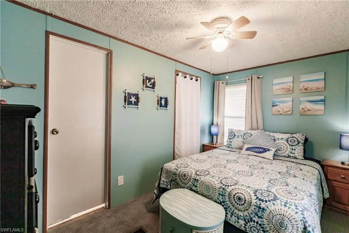 Bedroom with ceiling fan, crown molding, carpet floors, and a textured ceiling