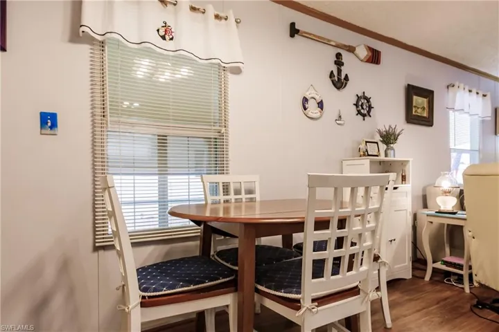 Dining space featuring laminate wood-style floors, crown molding, and a wealth of natural light