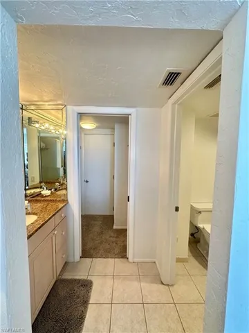Bathroom with tile patterned flooring, vanity, baseboards, and visible vents