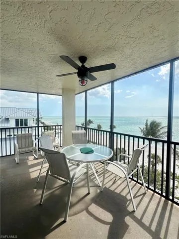 Sunroom / solarium featuring a water view and a ceiling fan