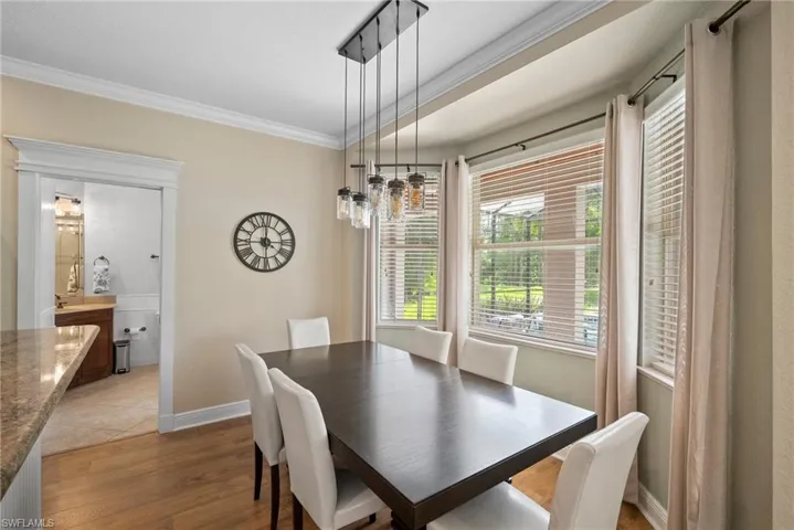 Dining area with hardwood / wood-style flooring and crown molding