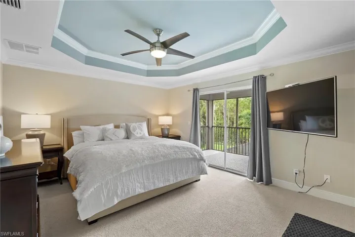 Carpeted bedroom with ceiling fan, crown molding, access to outside, and a tray ceiling