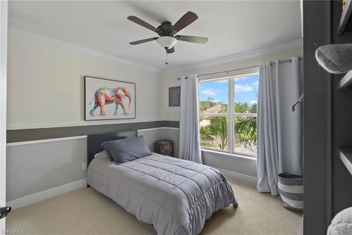 Bedroom featuring ceiling fan, ornamental molding, and light colored carpet