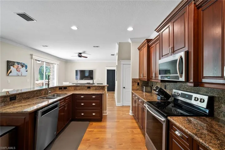 Kitchen featuring stainless steel appliances, ceiling fan, sink, backsplash, and light hardwood / wood-style flooring