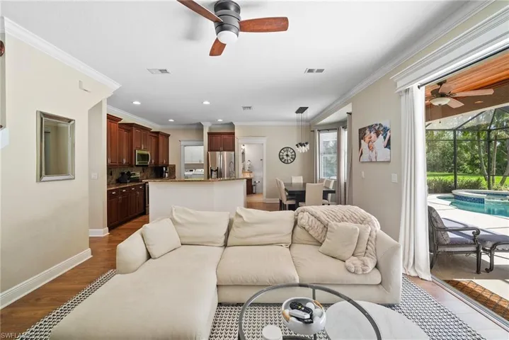 Living room featuring ceiling fan, wood-type flooring, and crown molding