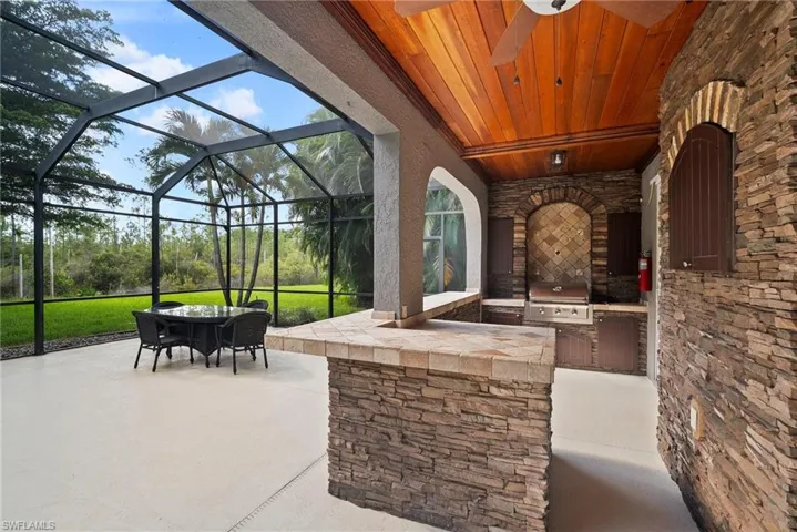 View of patio / terrace with glass enclosure, ceiling fan, a grill, and exterior kitchen