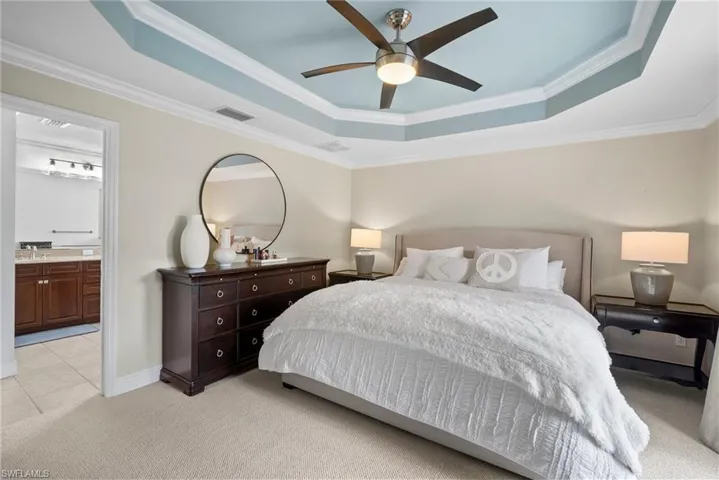 Bedroom with ceiling fan, a raised ceiling, and crown molding