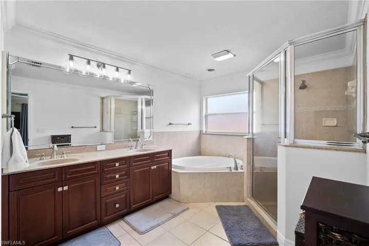 Bathroom with ornamental molding, tile patterned floors, plus walk in shower, and dual vanity