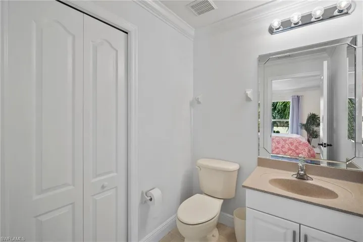 Bathroom with crown molding, vanity, and toilet