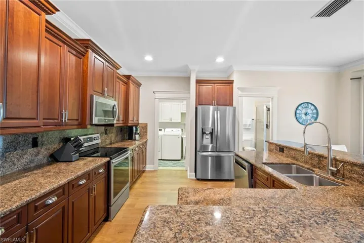 Kitchen with light wood-type flooring, stainless steel appliances, dark stone countertops, sink, and decorative backsplash
