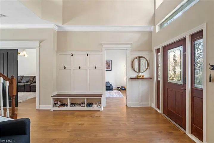 Entryway featuring a towering ceiling, light wood-type flooring, and crown molding
