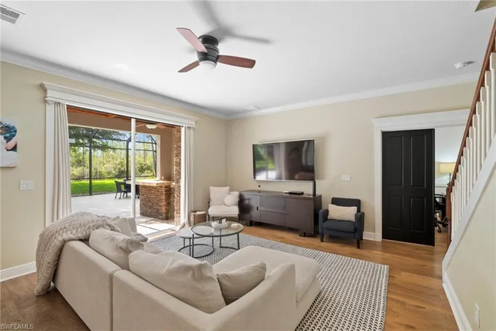 Living room with ceiling fan, wood-type flooring, and ornamental molding