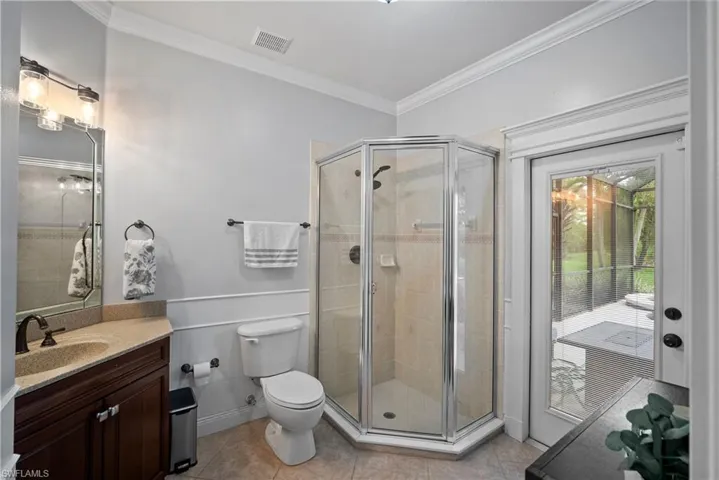 Bathroom with an enclosed shower, toilet, vanity, and tile patterned flooring