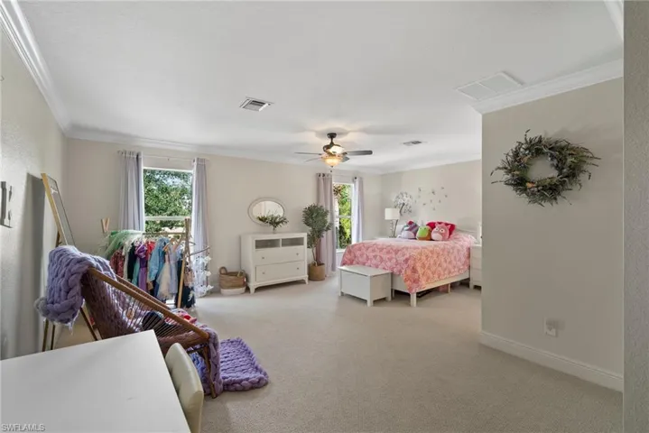 Carpeted bedroom featuring ceiling fan and ornamental molding