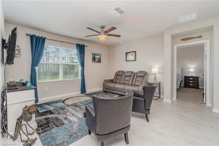 Living room featuring light plank tile flooring and ceiling fan light