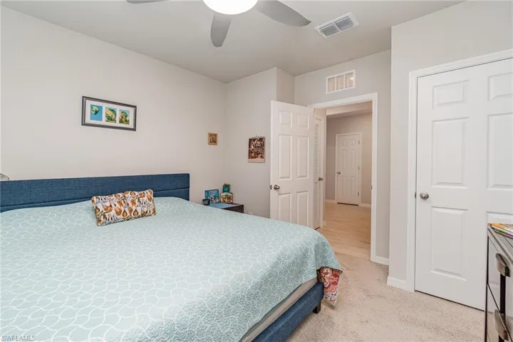 Bedroom featuring light colored carpet and ceiling fan light