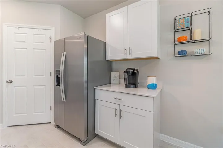Kitchen featuring white cabinets and stainless steel refrigerator with ice dispenser