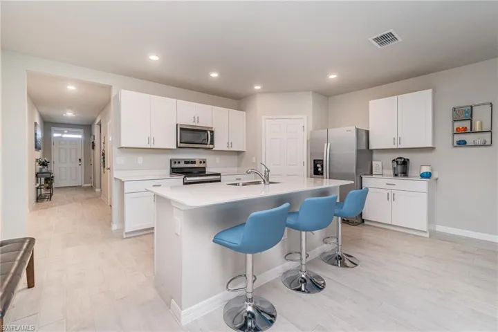 Kitchen with stainless steel appliances, an island with sink, a kitchen breakfast bar, and white cabinets