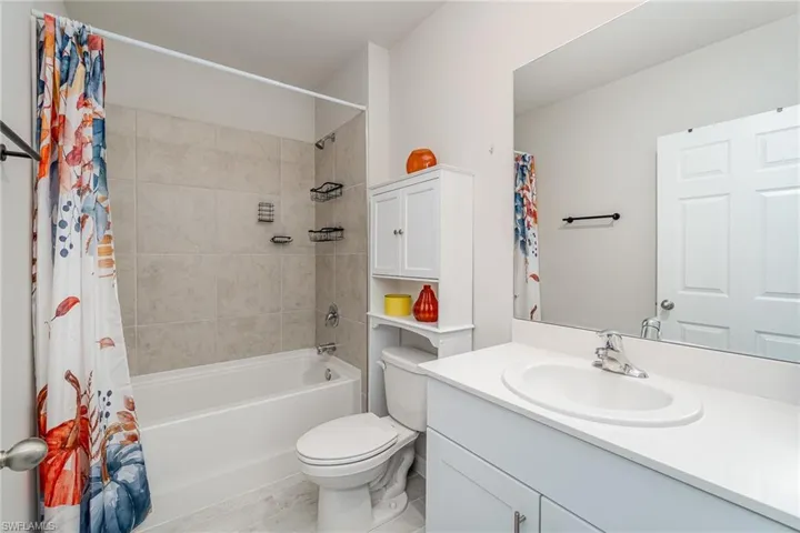 Full bathroom with vanity, commode, and shower / bath combination with curtain