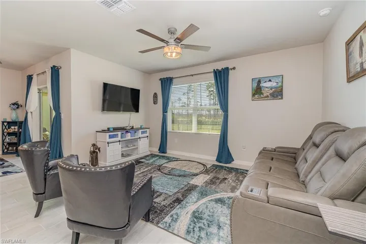 Living room with light plank tile floors and ceiling fan light