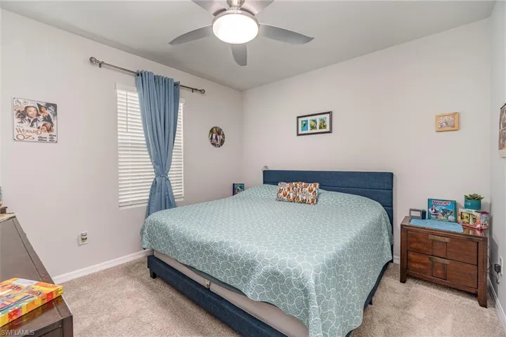 Bedroom featuring light colored carpet and ceiling fan light