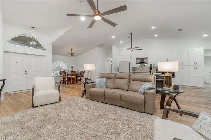 Living room featuring ceiling fan with notable light wood-type flooring, and high vaulted ceiling