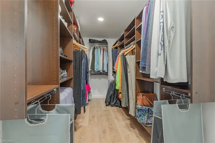 Spacious closet  with beautiful closet organizers and featuring light hardwood / wood-style flooring