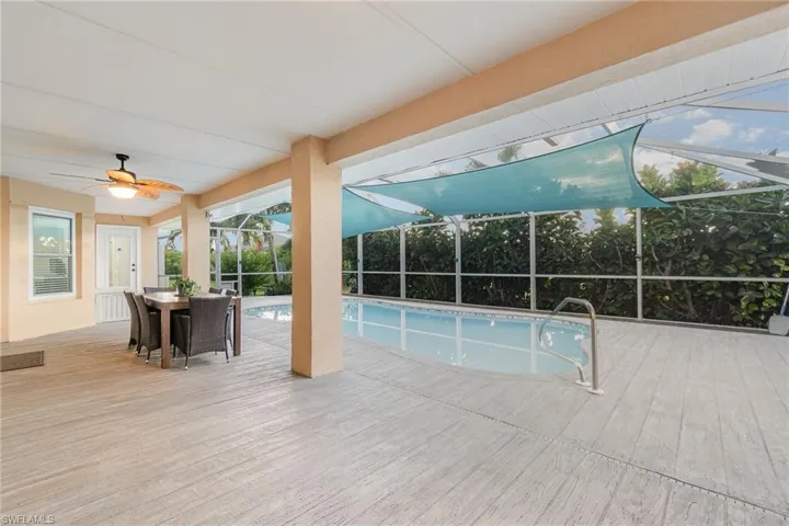 View of swimming pool featuring a lanai, ceiling fan, and wood llike concrete pool deck