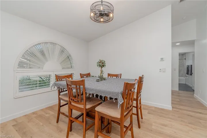 Dining space with a notable chandelier, light wood-type flooring, and vaulted ceiling