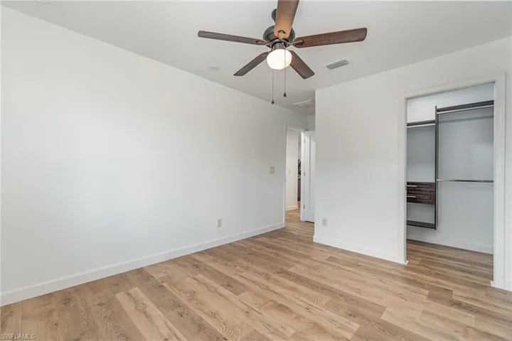 Unfurnished bedroom with light wood-type flooring, ceiling fan, and a closet with organizer