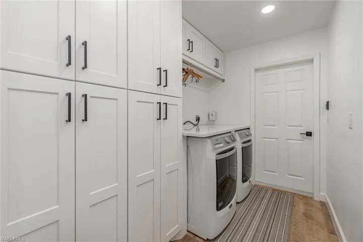 Laundry room with  a lot of cabinets, light hardwood / wood-style floors, and independent washer and dryer and drying rod to hang dry clothing