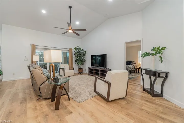 Living room featuring light wood-type flooring, ceiling fan, and high vaulted ceiling