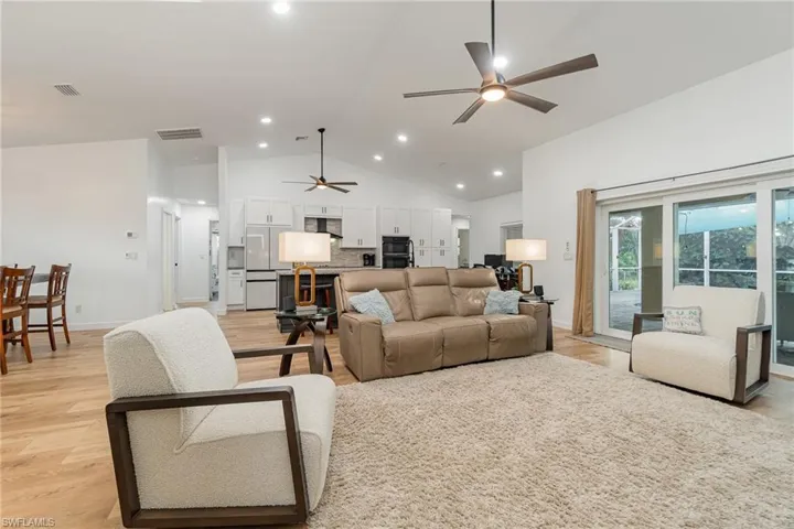 Living room with light wood-type flooring, vaulted ceiling, and ceiling fan